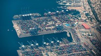 Pemandangan kapal barang besar, kapal laut yang merapat saat bongkar - muat peti kemas dan kargo via crane di dermaga pelabuhan di terminal logistik dan peti kemas Perama dekat pelabuhan niaga Piraeus dengan ribuan peti kemas bertumpuk.