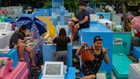 Mereka menyantap makan siang bersama sambil dengan membawa piring, tikar, payung serta makanan.