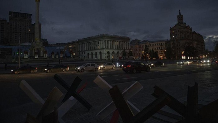 Cars pass in Independence Square at twilight in Kyiv, Ukraine, Monday, Oct. 31, 2022. Rolling blackouts are increasing across Ukraine as the government rushes to stabilise the energy grid and repair the system ahead of winter. (AP Photo/Andrew Kravchenko)
