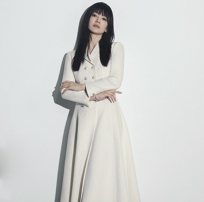 Dalam salah satu foto, Song Hye Kyo terlihat chic memakai gaun putih dengan desain double breasted dan rok panjang flare. Foto: dok. Instagram @songhyekyo_indonesia