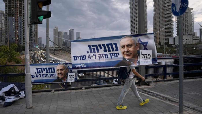 File - A man walks behind a Likud party election campaign banner depicting its leader, former Israeli Prime Minister Benjamin Netanyahu, in Tel Aviv, Israel, Thursday, Oct. 20, 2022. Israel is heading into its fifth election in under four years on Nov. 1. Hebrew on banner reads 