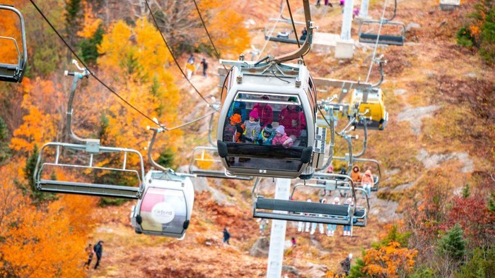 Visitors take pictures as others ride the ski-lift to Mont-Orford in the Mont-Orford National Park near Orford, Quebec, Canada, on October 8, 2022. (Photo by Sebastien ST-JEAN / AFP) (Photo by SEBASTIEN ST-JEAN/AFP via Getty Images)
