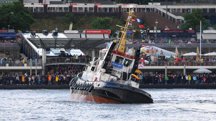 17 September 2022, Hamburg: Onlookers watch several tugboats perform the traditional tugboat ballet on the Elbe in front of the Landungsbrücken. Four tugs, maneuverable boats with up to 3,000 horsepower, have danced to classical music on the water, so to speak, for what the city says is a unique spectacle worldwide. Photo: Jonas Walzberg/dpa (Photo by Jonas Walzberg/picture alliance via Getty Images)