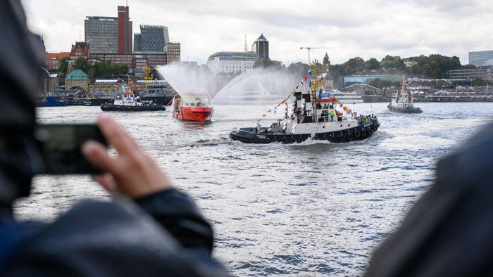 17 September 2022, Hamburg: Onlookers watch several tugboats perform the traditional tugboat ballet on the Elbe in front of the Landungsbrücken. Four tugs, maneuverable boats with up to 3,000 horsepower, have danced to classical music on the water, so to speak, for what the city says is a unique spectacle worldwide. Photo: Jonas Walzberg/dpa (Photo by Jonas Walzberg/picture alliance via Getty Images)