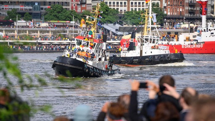 17 September 2022, Hamburg: Onlookers watch several tugboats perform the traditional tugboat ballet on the Elbe in front of the Landungsbrücken. Four tugs, maneuverable boats with up to 3,000 horsepower, have danced to classical music on the water, so to speak, for what the city says is a unique spectacle worldwide. Photo: Jonas Walzberg/dpa (Photo by Jonas Walzberg/picture alliance via Getty Images)