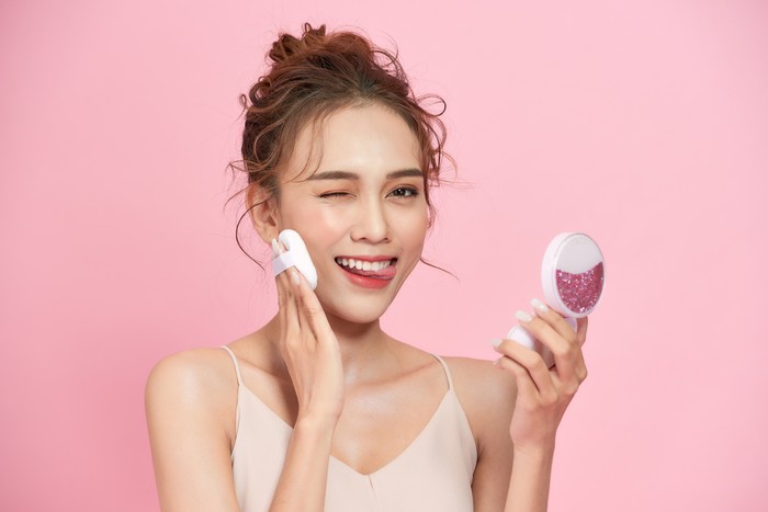 Young woman putting powder on her face