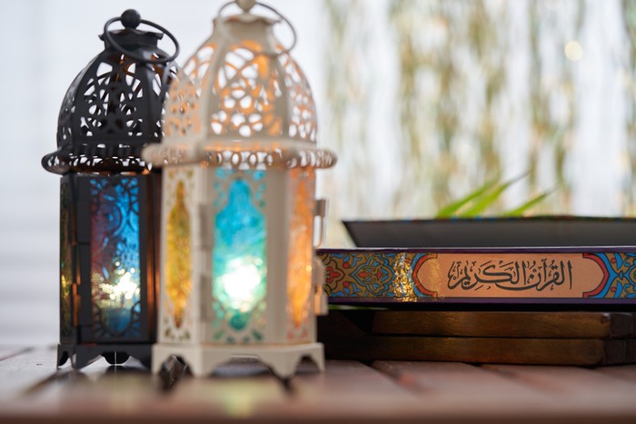 Ornamental Arabic lantern with burning candle glowing and holy book koran