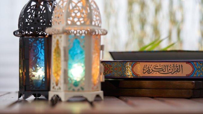 Ornamental Arabic lantern with burning candle glowing and holy book koran
