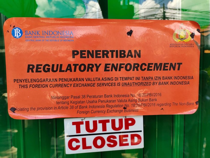 Pemasangan stiker pada money changer yang diduga ilegal di Kuta, Bali, Selasa (1/11/2022)