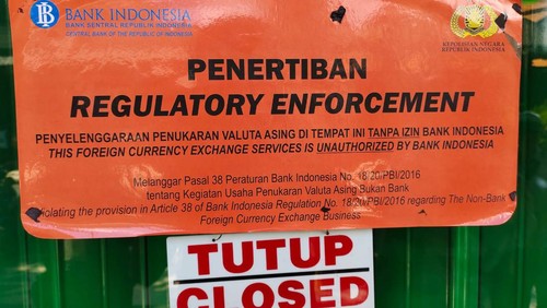 Pemasangan stiker pada money changer yang diduga ilegal di Kuta, Bali, Selasa (1/11/2022)