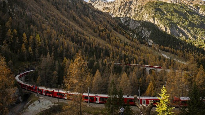 A train of the Rhaetian Railway (RHB) is on its way to set a world record for longest passenger train, on Saturday, October 29, 2022, in Preda, Switzerland. The 1.91 kilometer long train is on a journey on the UNESCO world heritage track from Preda to Alvaneu. The train consists of 100 waggons. The old world record of 1732,9 meters dates back to 1991. (Gian Ehrenzeller/Keystone via AP)