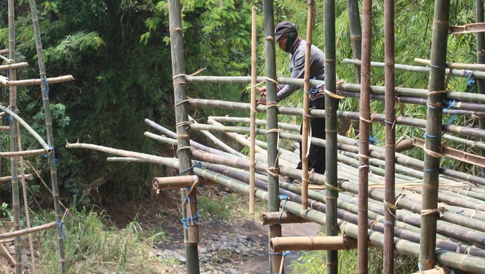 Warga bergotong royong membuat jembatan bambu di Desa Ngadi, Kediri, Jawa Timur, Rabu (2/11/2022). Jembatan bambu setinggi 40 meter penghubung Kediri dengan Tulungagung tersebut dibuat kembali setelah sebelumnya rusak terbawa arus sungai. ANTARA FOTO/Prasetia Fauzani/rwa.