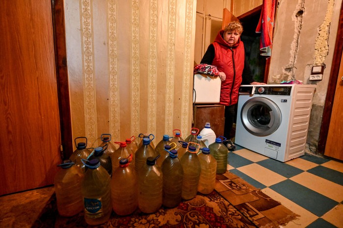 STEPNOHIRSK, UKRAINE - NOVEMBER 2, 2022 - A cat sits by a bucket of water that is being delivered by a farmer to local residents as the urban-type settlement close to the front line has had no water supply for eight months due to the shelling by Russian troops, Stepnohirsk, Zaporizhzhia Region, southeastern Ukraine. (Photo credit should read Dmytro Smolienko / Ukrinform/Future Publishing via Getty Images)