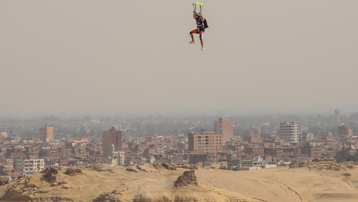 Aksi Penerjun Payung Meluncur di Atas Piramida Mesir GIZA, EGYPT - NOVEMBER 02: Skydivers fly over the pyramids of Giza during the skydiving festival with the participation of more than a thousand skydivers from 20 states on November 02, 2022, in Giza, Egypt. (Photo by Mohamed Abdel Hamid/Anadolu Agency via Getty Images)