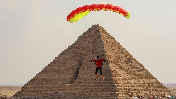 Penerjun payung terbang di atas piramida Giza selama festival terjun payung di Giza, Mesir, Rabu (2/11/2022).