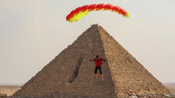 Aksi Penerjun Payung Meluncur di Atas Piramida Mesir GIZA, EGYPT - NOVEMBER 02: Skydivers fly over the pyramids of Giza during the skydiving festival with the participation of more than a thousand skydivers from 20 states on November 02, 2022, in Giza, Egypt. (Photo by Mohamed Abdel Hamid/Anadolu Agency via Getty Images)