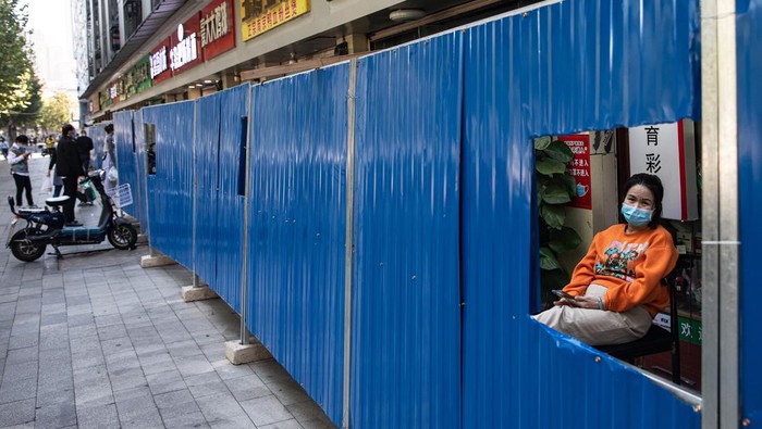 COVID-19 Pulang Kampung, Wuhan Lockdown Lagi WUHAN, CHINA - NOVEMBER:(CHINA OUT) A resident wears a mask in front of makeshift barricade wall built to control entry and exit to a residential compound behind which a vendor cooks on November 2,2022 in Wuhan, Hubei Province, China.(Photo by Getty Images)