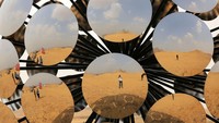 Pengunjung tercermin dalam instalasi Orb: Under the same Sun oleh seniman internasional yang berbasis di Madrid SpY. Pameran karya seni kontemporer The Forever is Now kembali diadakan di kawasan Piramida Giza, Mesir, untuk kedua kalinya. Getty Images/Fadel Dawod