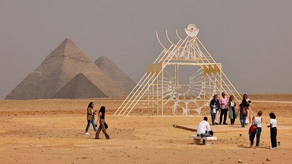 Pengunjung berpose untuk foto dengan instalasi A Pyramid In Other Vocabularies oleh seniman Mesir Ahmed Karaly. Khaled Desouki/AFP/Getty Images