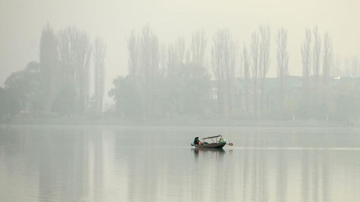Potret India Diselimuti Kabut Asap, Capai Level Berbahaya A man rows a boat in the waters of Dal Lake amid foggy conditions in Srinagar on November 2, 2022. (Photo by TAUSEEF MUSTAFA / AFP) (Photo by TAUSEEF MUSTAFA/AFP via Getty Images)