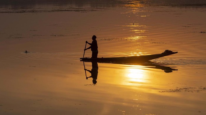 Kashmiri fishermen row their Shikaras, traditional boats, as the sun sets over the Dal Lake, on the outskirts of Srinagar, Indian controlled Kashmir, Wednesday, Nov. 2, 2022. (AP Photo/Dar Yasin)