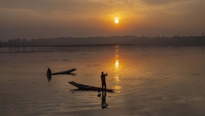 Kashmiri fishermen row their Shikaras, traditional boats, as the sun sets over the Dal Lake, on the outskirts of Srinagar, Indian controlled Kashmir, Wednesday, Nov. 2, 2022. (AP Photo/Dar Yasin)