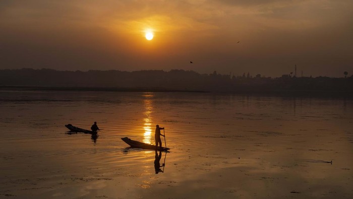 Kashmiri fishermen row their Shikaras, traditional boats, as the sun sets over the Dal Lake, on the outskirts of Srinagar, Indian controlled Kashmir, Wednesday, Nov. 2, 2022. (AP Photo/Dar Yasin)