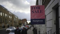 Warga berjalan di dekat papan pengumuman rumah yang dijual di London, 3 November 2022. AP Photo/Kin Cheung.