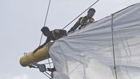 Mengembangkan layar saat diterpa ombak dan angin kencang bukanlah pekerjaan mudah. Berjalan di atas geladak KRI bima Suci-945 dalam situasi demikian seperti menaiki wahana “roller coster”, tubuh terasa terangkat, terhempas, dan perut terguncang mengikuti alur ombak.