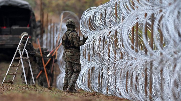 Polandia Pasang Pagar Berduri di Perbatasan dengan Rusia Polish soldiers begin laying a razor wire barrier along Polandβs border with the Russian exclave of Kaliningrad in Wisztyniec, Poland, on Wednesday Nov. 2, 2022. Polandβs government ordered the construction of the barrier after Russiaβs aviation authority decided to launch flights from the Middle East and North Africa to Kaliningrad. The Polish government said it was acting to prevent a migration crisis at that border. (AP Photo/Michal Kosc)