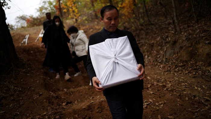Lee Hyo-sook, 61, mother of Jung Joo-hee, 30, who was one of the victims of a crowd crush that happened during Halloween festivities, grieves next to her daughter's grave in Namyangju, South Korea, November 3, 2022. REUTERS/Kim Hong-Ji