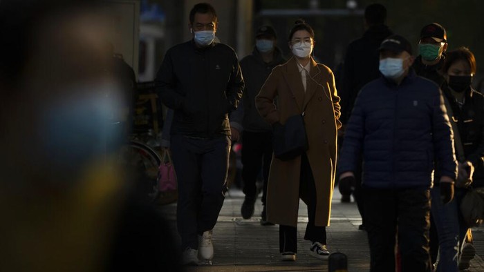 Ramai-ramai Buruh Tinggalkan Zona Industri Zhengzhou Imbas Lockdown Commuters wearing face masks walk along a street in the central business district in Beijing, Thursday, Nov. 3, 2022. Access to an industrial zone in the central Chinese city of Zhengzhou was suspended Wednesday after the city reported dozens of coronavirus cases and workers who assemble Apple Inc. iPhones left their factory in the zone following outbreaks. (AP Photo/Mark Schiefelbein)