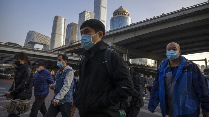 Commuters wearing face masks walk along a street in the central business district in Beijing, Thursday, Nov. 3, 2022. Access to an industrial zone in the central Chinese city of Zhengzhou was suspended Wednesday after the city reported dozens of coronavirus cases and workers who assemble Apple Inc. iPhones left their factory in the zone following outbreaks. (AP Photo/Mark Schiefelbein)