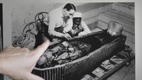 Seorang turis berbicara di depan gambar yang menunjukkan arkeolog Inggris Howard Carter di depan sarkofagus Raja Tutankhamun di makamnya Lembah Para Raja di Luxor, Mesir, Jumat, 4 November 2022.