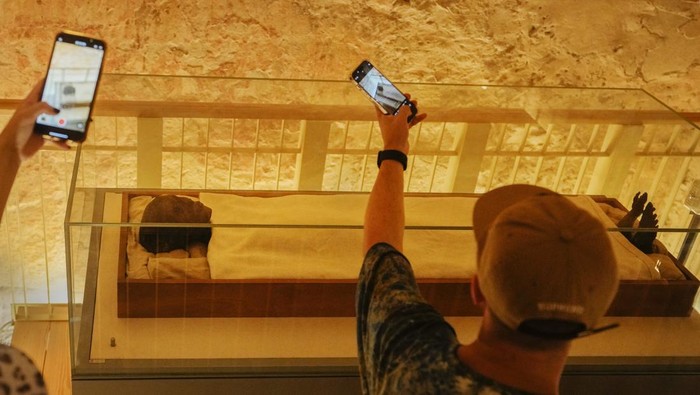 100 Tahun Penemuan Makam Tutankhamun, Yuk Lihat Perayaannya Tourists film the Tutankhamun's mummy at his tomb at the Valley of the Kings in Luxor, Egypt, Friday, Nov. 4, 2022. Egypt celebrates the 100-year anniversary of the discovery of Tutankhamun tomb on Nov. 4, 1922 by British archaeologist Howard Carter and his team. (AP Photo/Amr Nabil)