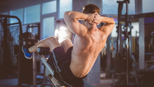 Young fitness man doing incline sit-up exersises