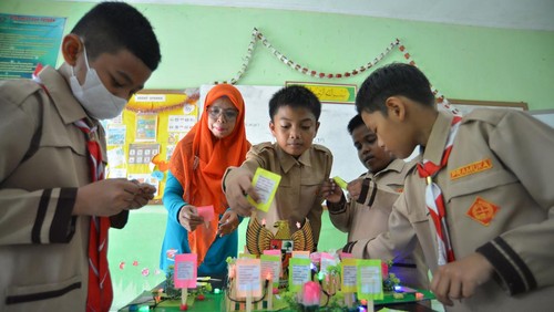 Guru kelas 6 Asmidar (kedua kiri), mendampingi murid-muridnya belajar menggunakan kotak Pancasila yang ia ciptakan, di Madrasah Ibtidaiyah Negeri (MIN) 3 Gunung Pangilun, Padang, Sumatera Barat, Sabtu (5/11/2022). Asmidar menciptakan media pembelajaran kotak pancasila dari kardus bekas dan stik es krim yang berisi penerapan lima sila dalam kehidupan sehari-hari yang terlebih dahulu sudah dibahas melalui aplikasi Abelpa (Asik Belajar Pancasila) agar murid-muridnya cepat paham. ANTARA FOTO/Iggoy el Fitra/YU