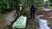 Warga menunjukkan salah satu makam yang terseret banjir hingga ke pinggir sungai di TPU Embah Besar, Desa Krikilan, Glenmore, Banyuwangi, Jawa Timur, Jumat (4/11/2022).