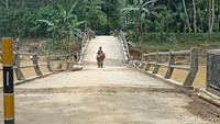 Saat ini masyarakat setempat bergotong royong untuk membersihkan timbunan kayu dan material sampah yang tersangkut kaki jembatan. (Foto: Adhar Muttaqin/detikJatim)