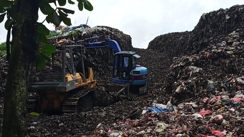 Proses pembelahan bukit sampah sebagai jalan untuk keluar truk pengangkut sampah yang keluar masuk ke sisi timur TPA Mandung, Tabanan. (Istimewa)