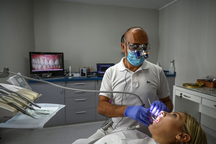 A dentist and his assistant work on a patient at a dental clinic in Istanbul on September 16, 2022. - Attracted by unbeatable prices, fast turnaround times and the promise of a bright smile, 150,000 to 250,000 foreign patients will travel to Turkey for treatment this year, according to the Turkish Dental Association (TDB), making the country one of the main destinations of world dental tourism. (Photo by Ozan KOSE / AFP) (Photo by OZAN KOSE/AFP via Getty Images)
