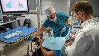 Seorang dokter gigi dan asistennya menangani pasien di klinik gigi di Istanbul, Jumat, (16/9/2022). Liburan gigi atau wisata gigi di Turki kini sedang booming.