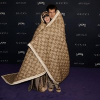 Selimut Gucci ukuran besar membungkus Billie Eilish dan Jesse Rutherford yang saling berpelukan saat berpose di depan para juru foto. Foto: FilmMagic/Steve Granitz via Getty Images