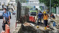 Warga melintas di samping proyek revitalisasi trotoar dan saluran air di Jl Medan Merdeka Timur, Gambir, Jakarta Pusat, Senin (7/11/2022).