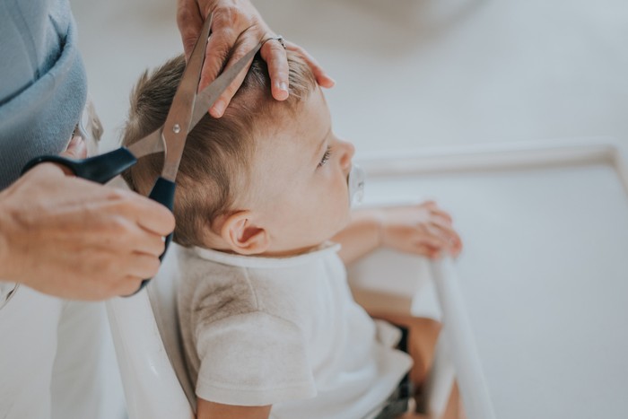 Mother cutting his baby boy hair at home