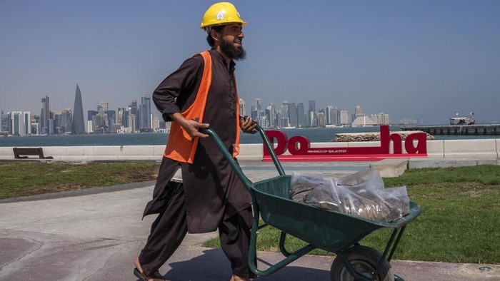 A Pakistani migrant laborer works on the corniche, overlooking the skyline of Doha, Qatar, Wednesday, Oct. 19, 2022. One of the world’s biggest sporting events has thrown an uncomfortable spotlight on Qatar’s labor system, which links workers’ visas to employers and keeps wages low for workers toiling in difficult conditions. (AP Photo/Nariman El-Mofty)