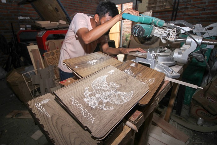 Perajin menyelesaikan pembuatan kerajinan kayu suvenir resmi KTT G20 Bali di Kawasan Wedoro, Sidoarjo, Jawa Timur, Senin (7/11/2022). Kerajinan kayu dengan motif peta Indonesia, cover buku, cover binder berlambang Burung Garuda Pancasila dan kotak pensil tersebut terpilih menjadi salah satu dari 20 produk UMKM yang lolos kurasi Kementerian Koperasi dan UKM (KemenkopUKM) sebagai suvenir resmi KTT G20 di Bali. ANTARA FOTO/Umarul Faruq/wsj.