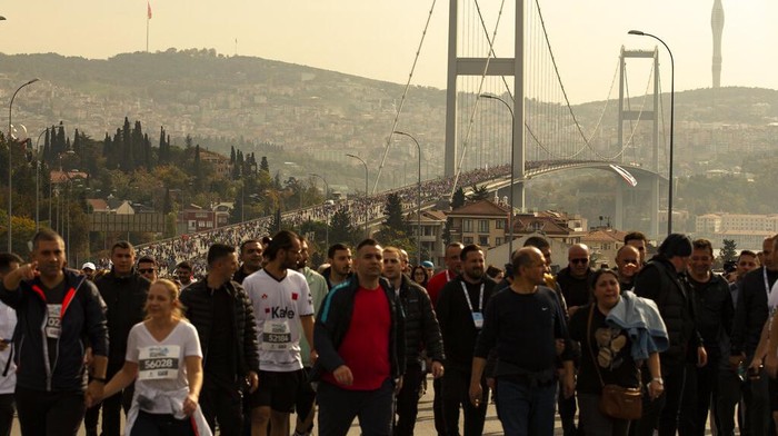 Ribuan Pelari Ikut Maraton Lintas Benua di Turkiaine War Ikaria Angel bulk cargo ship, which departed from Ukrainian port of Chornomorsk, sails under 15th July Martyrs bridge over the Bosphorus as runners take part in a Marathon in Istanbul, Turkey, Sunday, Nov. 6, 2022. (AP Photo/Emrah Gurel)