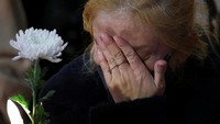 Seorang wanita memegang bunga dan menitikan air mata saat acara peringatan tragedi Itaewon. 