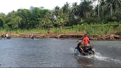 Warga melintasi sungai akibat akses jembatan putus di Banjar Sekarkejula Kelod, Desa Yehembang Kauh, Kecamatan Mendoyo, Kabupaten Jembrana, Bali. Senin (07/11/2022)